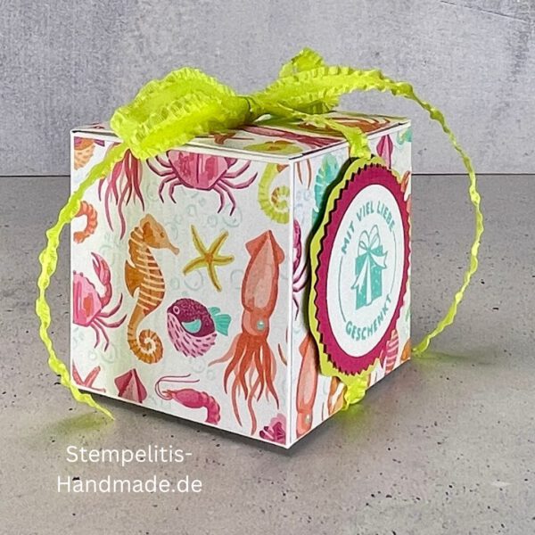 Handdekorierte Geschenkschachtel mit Schleife von oben, Geschenkschachtel mit liebevollem Aufkleber “Mit viel Liebe verschenkt”, Detailansicht Schleife auf Geschenkschachtel, Seitenansicht Geschenkschachtel mit buntem Designpapier, Offene Geschenkbox zum Befüllen, Geschenkschachtel auf hellem Hintergrund mit Dekorband, Handgemachte Geschenkverpackung mit grünem Band und Etikett